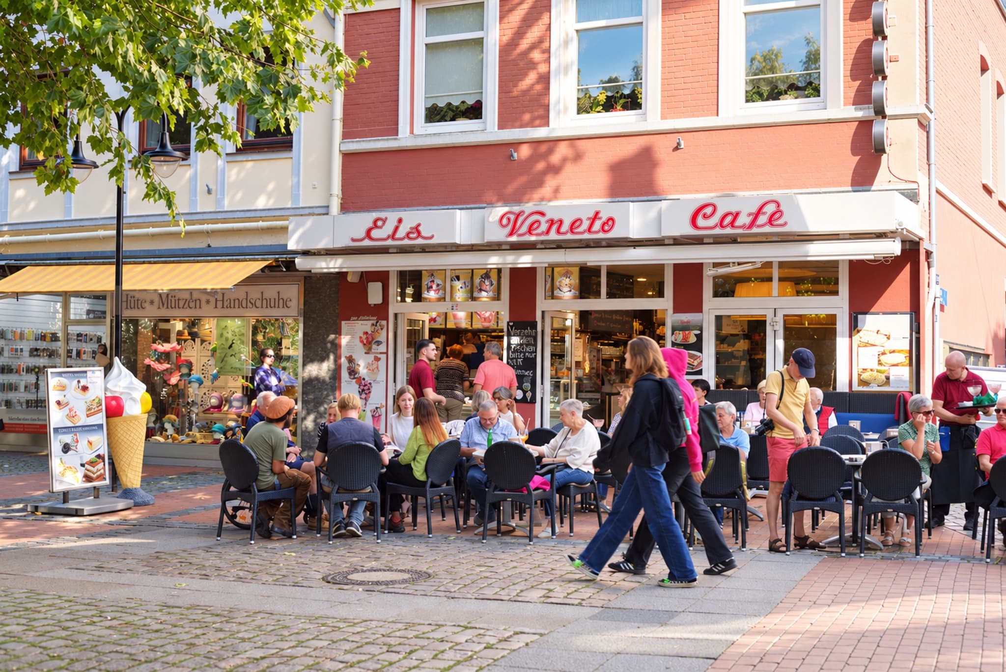 Eiscafé Veneto in der Einkaufsmeile — rote Eckfassade mit dem Schriftzug „Eis Veneto Café“ und voller Außenterrasse